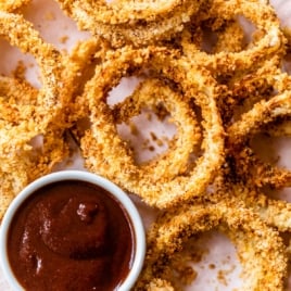a plate of crispy air fryer onion rings with dip sauce