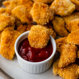 Baked chicken nuggets on platter with bowl of ketchup