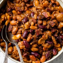 Overhead view of crockpot baked beans in bowl with two spoons