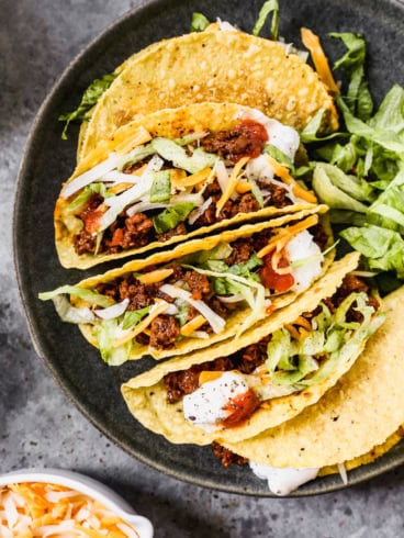 Hard shell ground beef tacos on plate with toppings