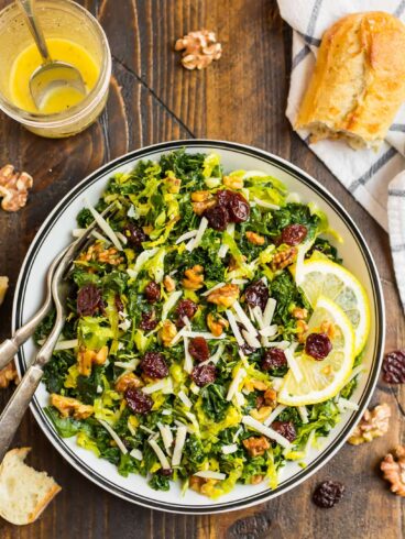 Kale and Brussel Sprout Salad with Maple Vinaigrette in a white salad bowl topped with walnuts
