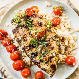 Overhead view of grilled pesto chicken and tomatoes over rice