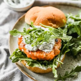 Salmon burger topped with yogurt herb sauce and arugula