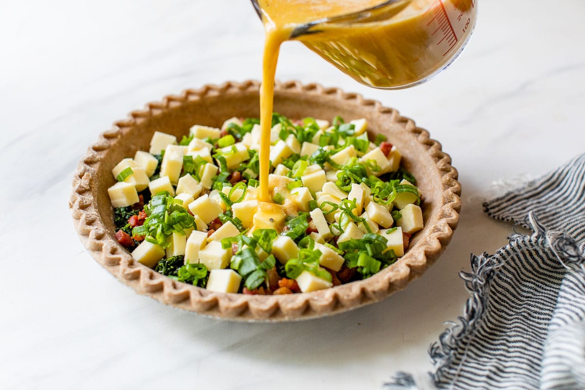 pouring the egg and milk custard into easy quiche