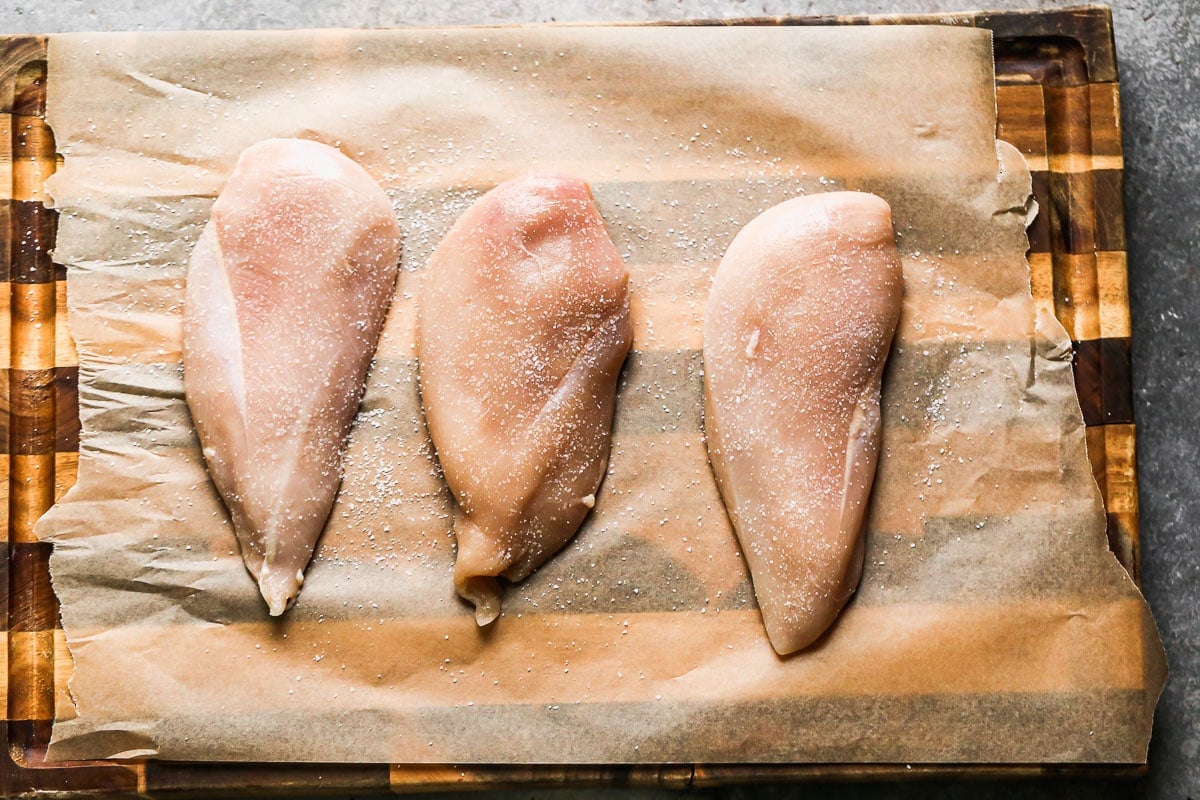 Three chicken breasts on a cutting board