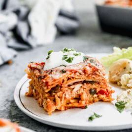 Healthy chicken tortilla casserole on a plate topped with Greek yogurt and cilantro