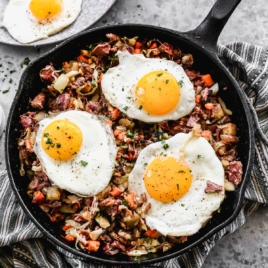corned beef hash with three eggs in a skillet