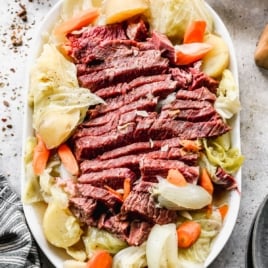 Sliced corned beef on a platter with carrots and cabbage