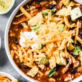 a bowl of crockpot chicken enchilada soup with cheese on top