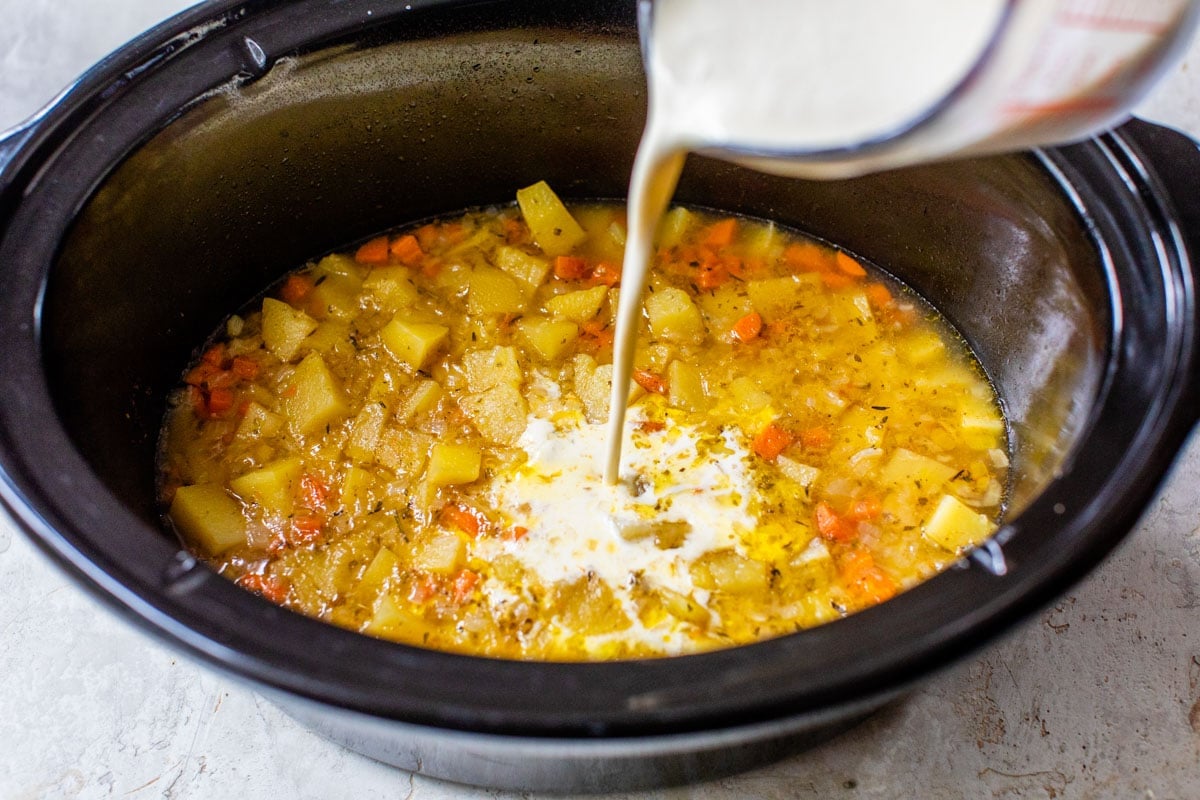A bowl of crockpot potato soup with bacon and crackers