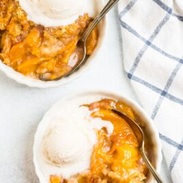 Easy Dutch Oven Peach Cobbler inside a dutch oven with fresh peaches.