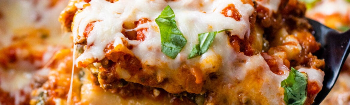 Crockpot lasagna being scooped out of a slow cooker