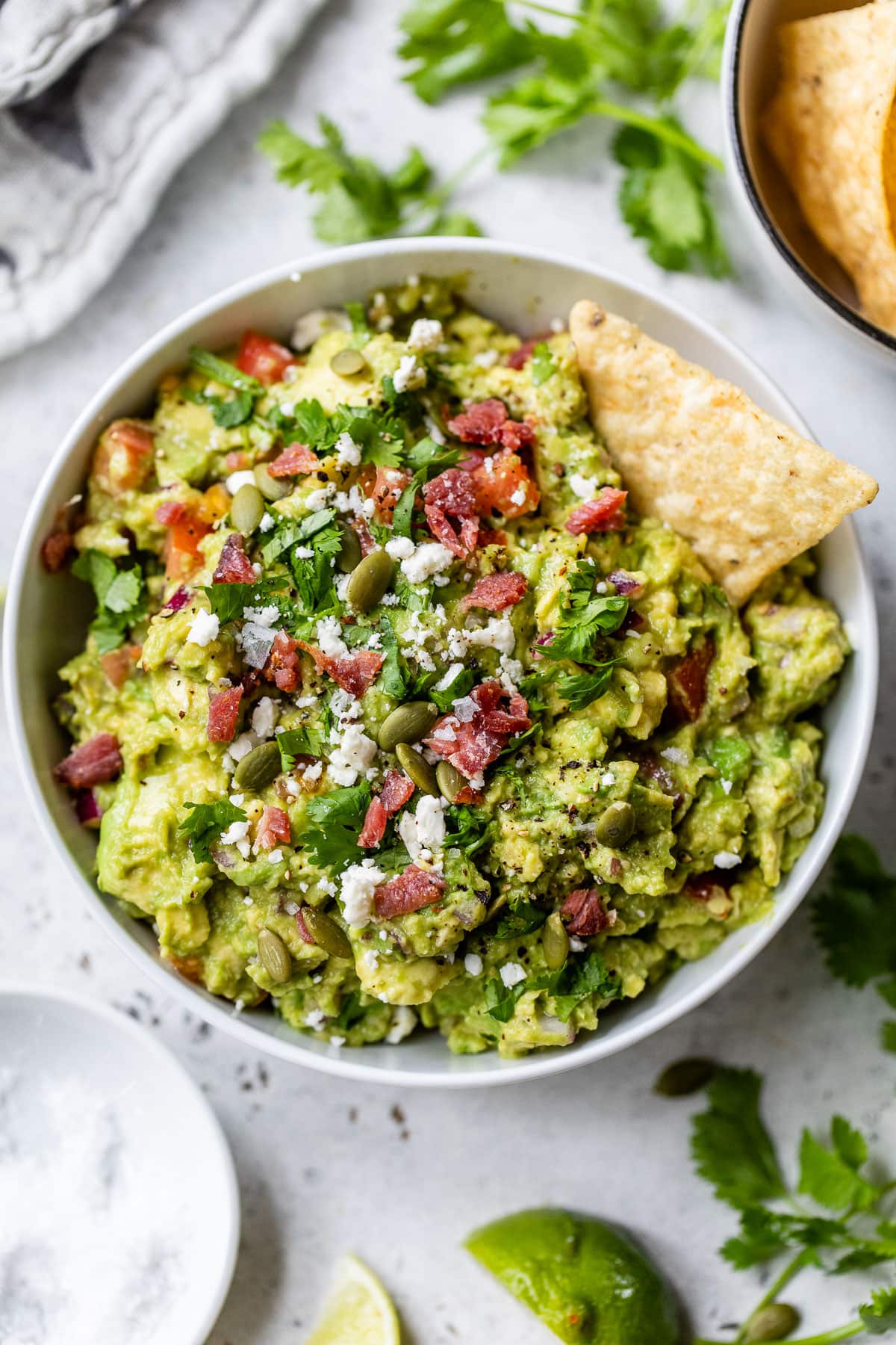 best guacamole recipe without jalapeno in a bowl topped with feta and bacon
