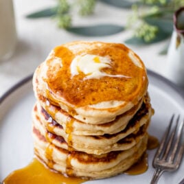 A stack of fluffy pancakes with butter and maple syrup