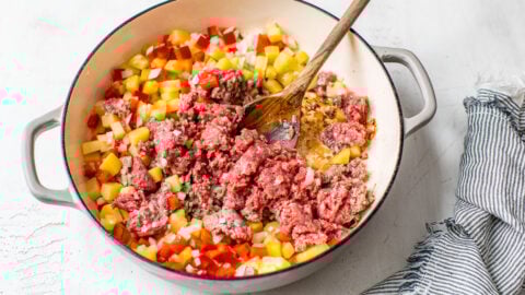 Raw meat being added to vegetables