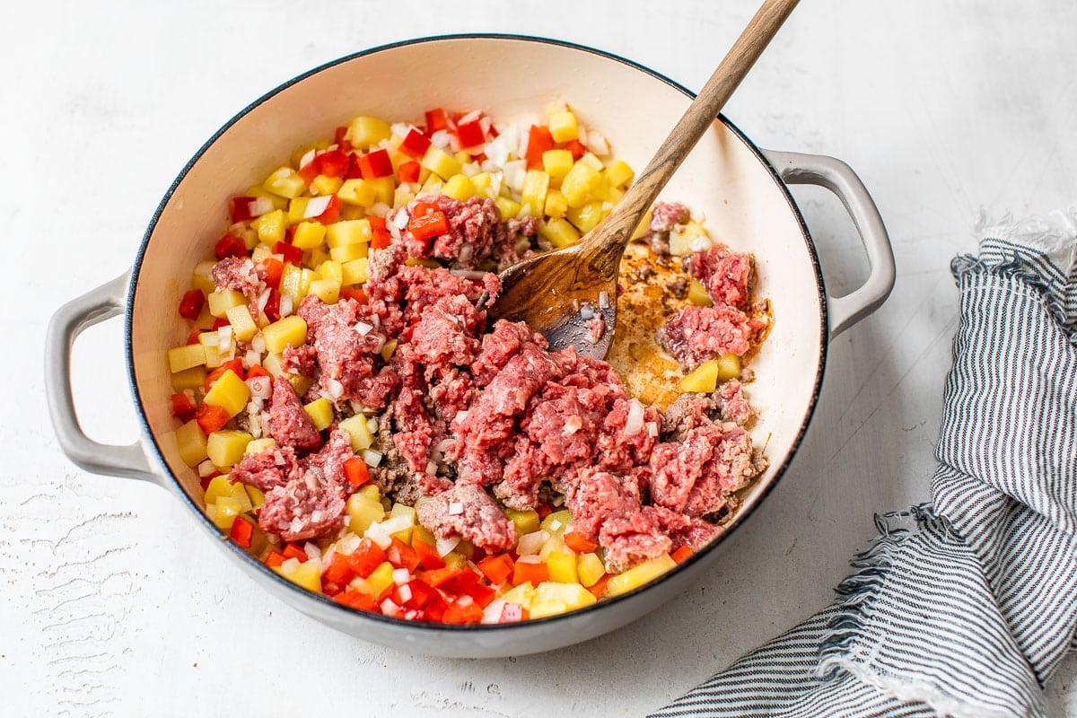 Raw meat being added to vegetables