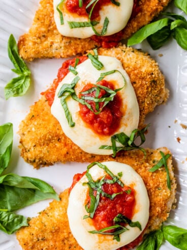 crispy and healthy oven baked chicken parmesan on a plate with mozzarella, tomato sauce, and basil