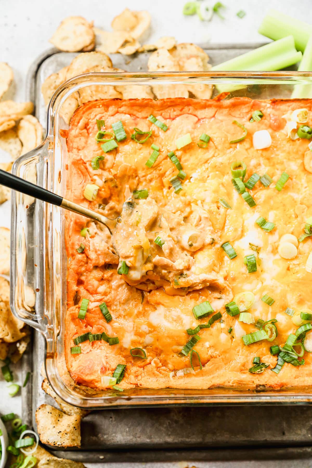 Creamy healthy Buffalo chicken dip in baking dish with spoon