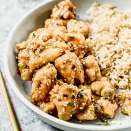 A plate of sesame chicken with rice
