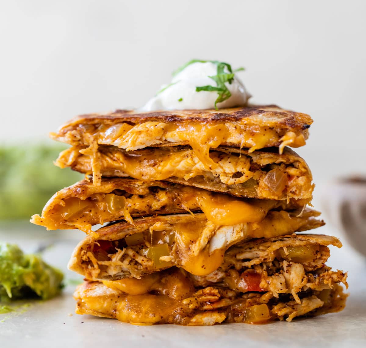 A stack of chicken quesadilla triangles with sour cream