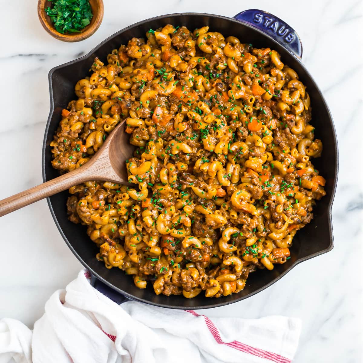 A spoon in a skillet of noodles and meat