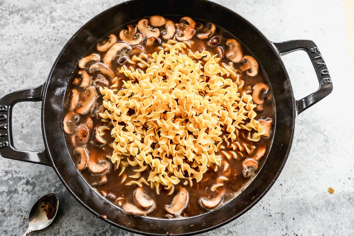 egg noodles added to a pan for beef stroganoff