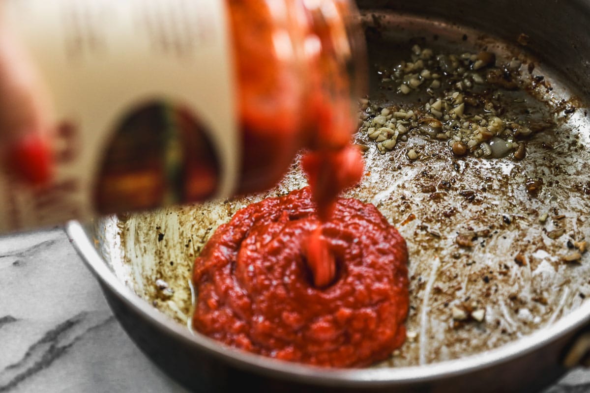 pouring pasta sauce into pan