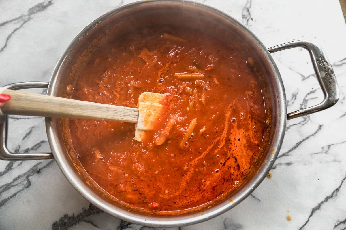 stirring marinara sauce and pasta in pot