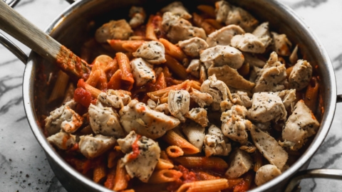 stirring chicken into skillet of pasta