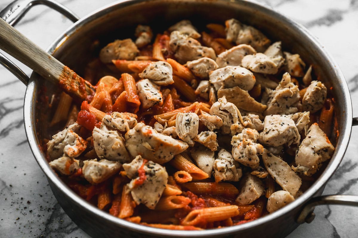 stirring chicken into skillet of pasta