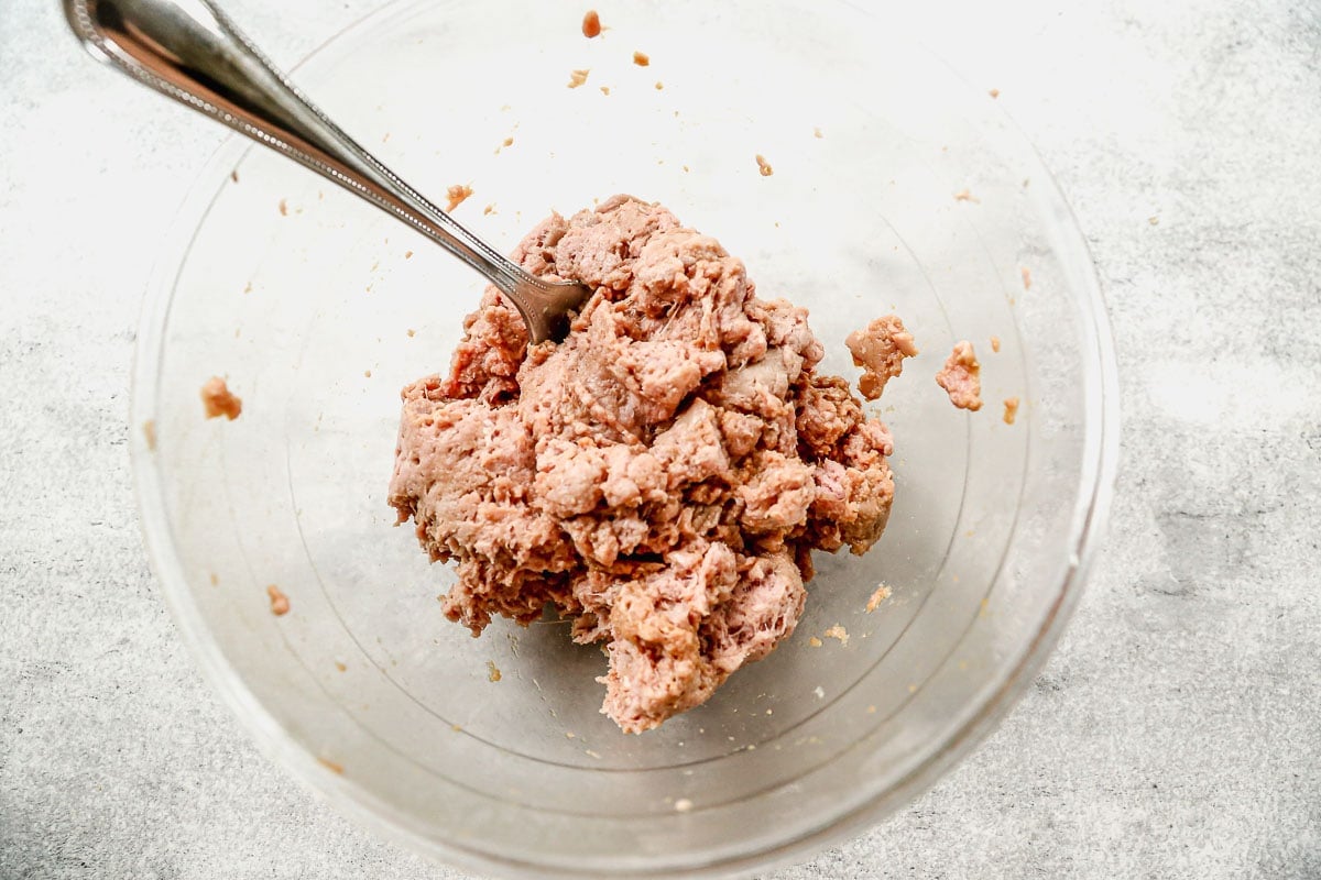 a glass bowl of uncooked ground turkey marinating in soy sauce