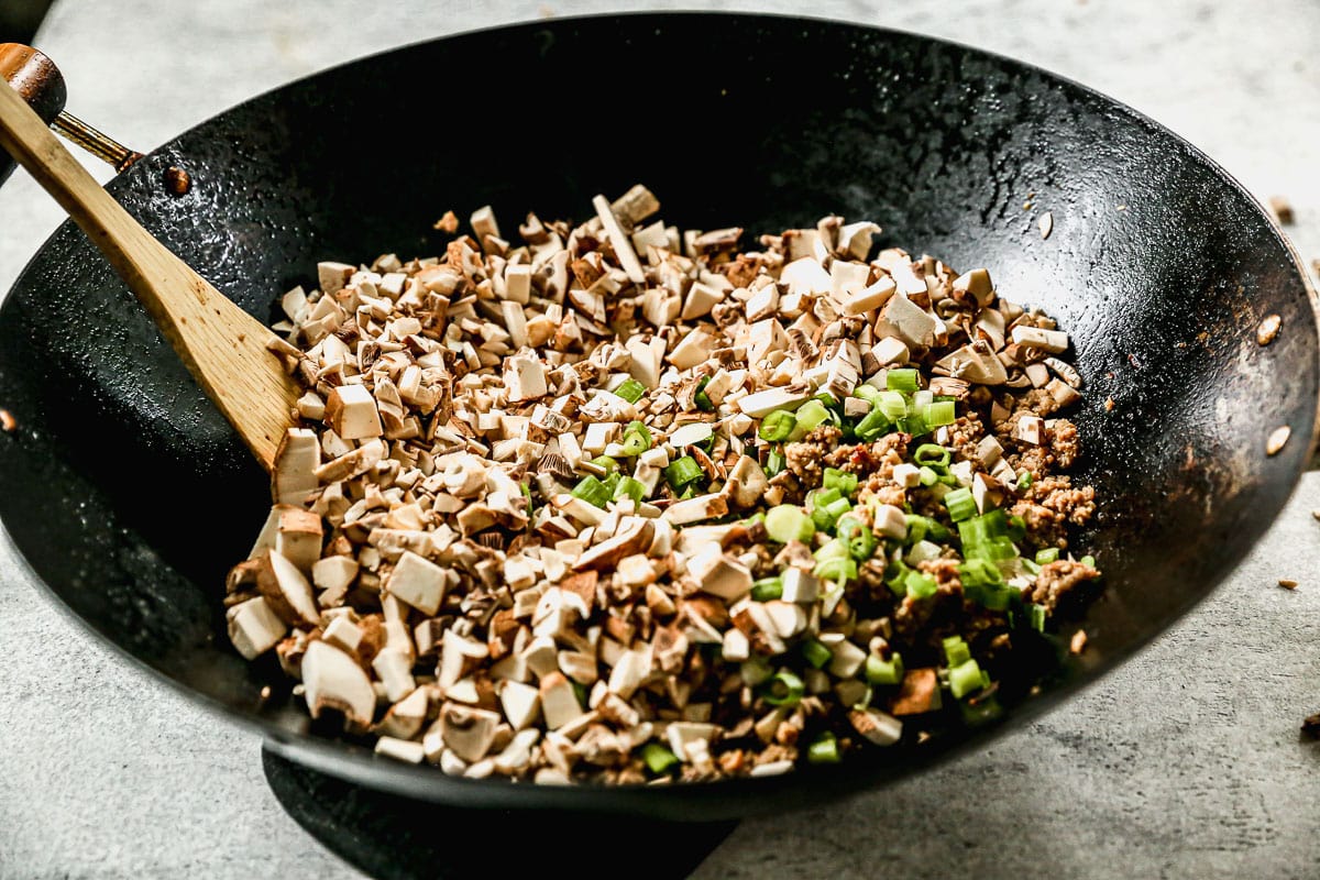 a wok of ground turkey and finely chopped mushrooms and green onions