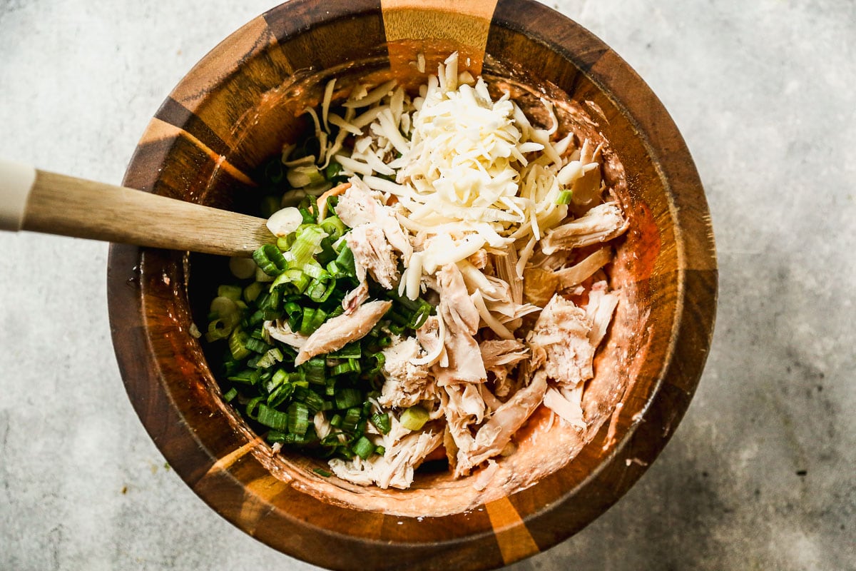 Shredded chicken, green onions, and mozzarella added to mixing bowl with dip