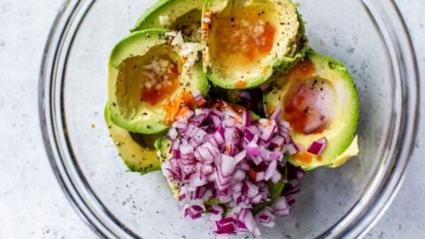 Avocados, red onion, garlic, and seasonings in a bowl