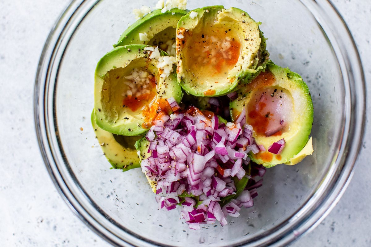 Avocados, red onion, garlic, and seasonings in a bowl