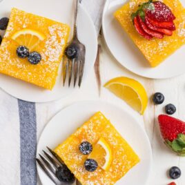 Three pieces of lemon poke cake on white plates