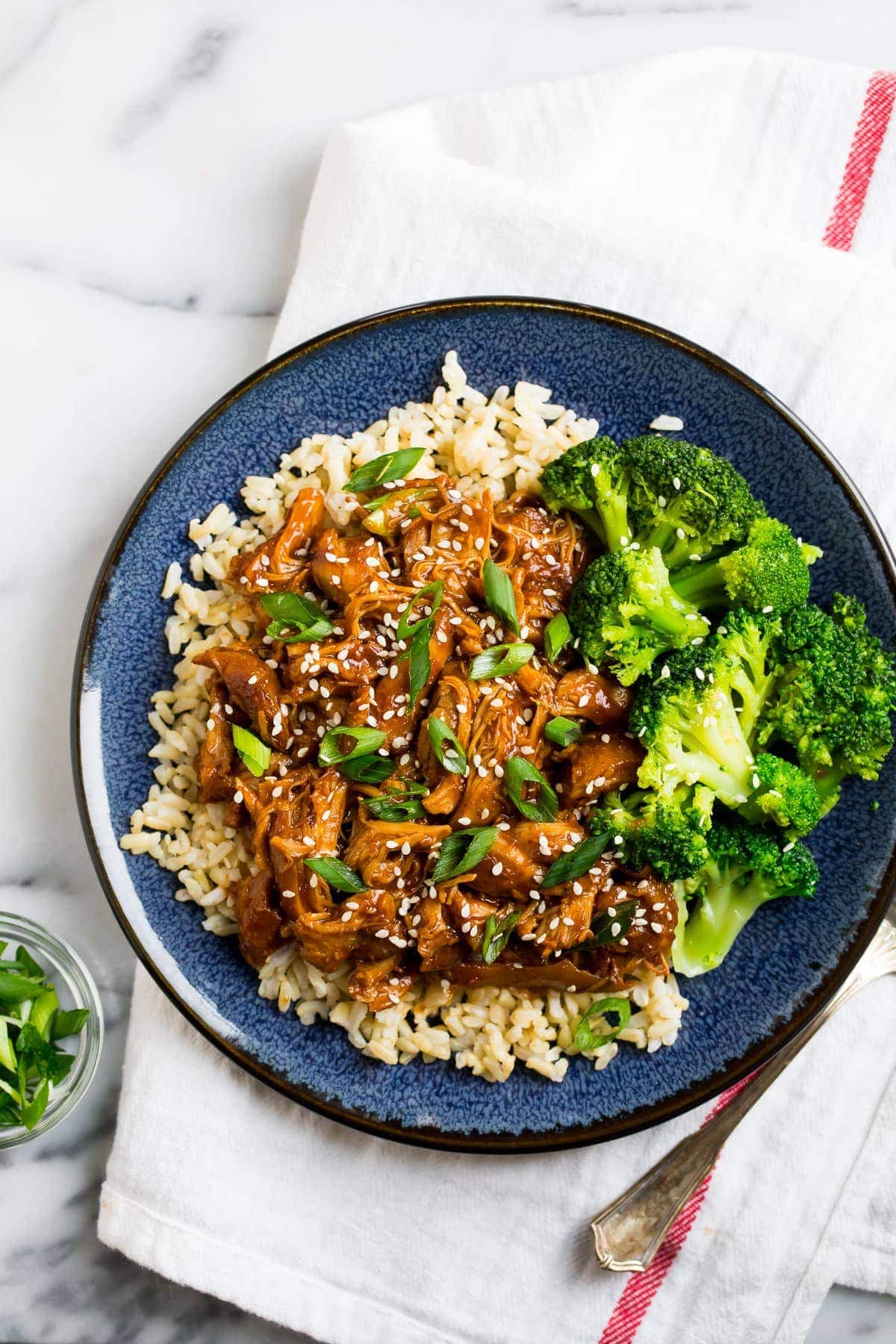 This healthy Slow Cooker Honey Garlic Chicken will quickly become a family favorite! Serve it as an easy dinner with rice and veggies! Healthy slow cooker honey garlic boneless skinless chicken thighs served on a plate with rice and broccoli