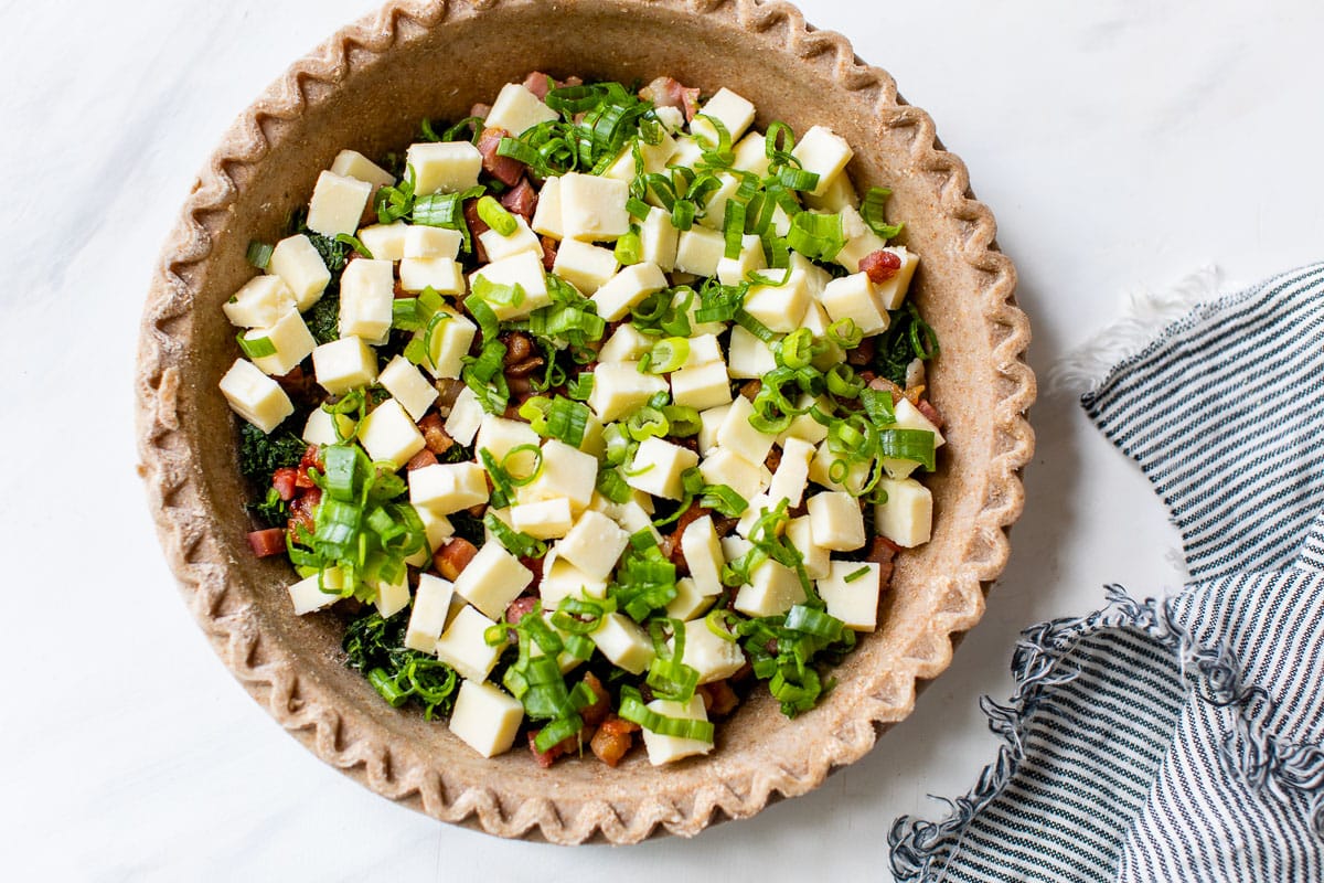 cheese, vegetables, and ham in a crust for quiche